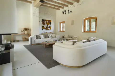Salón moderno con sofás blancos, chimenea y suelo de microcemento sobre azulejos.