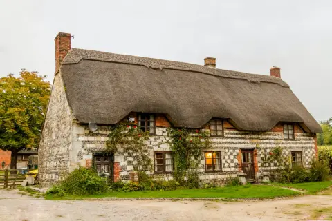 Casa con tetto di paglia e muri in pietra, con edera rampicante. Sembra un luogo tranquillo, ma forse nasconde problemi dopo vendita casa.