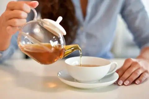 Kobieta nalewa aromatyczną herbatę z kopru włoskiego do filiżanki.