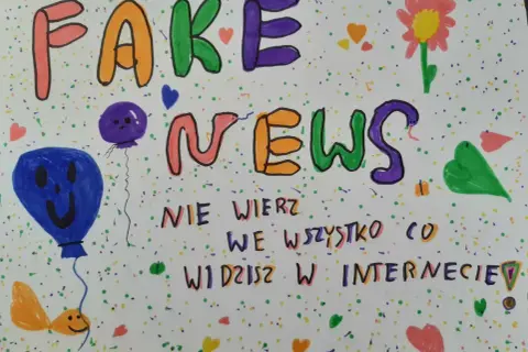 Kolorowe litery tworzą napis "FAKE NEWS". Poniżej, mniejszymi literami, widnieje ostrzeżenie: "NIE WIERZ WE WSZYSTKO CO WIDZISZ W INTERNECIE!". Obrazek ozdobiony jest balonami, kwiatkiem i serduszkami.