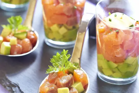 Délicieux tartare saumon fumé avocat servi en verrine et cuillère, garni de ciboulette.