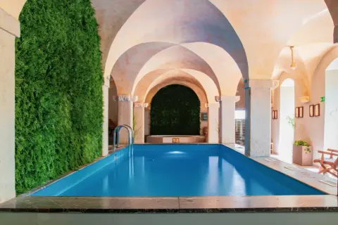 Relaks w hotelu spa na Dolnym Śląsku. Wnętrze z basenem, zieloną ścianą i łukowym sufitem.