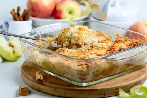 Ein goldbrauner Apfelkuchen mit knuspriger Streuseldecke und Mandelblättchen, bereit zum Servieren.
