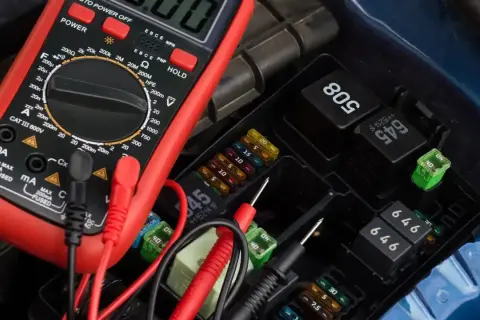 A multimeter is used to test a car's fuse box and relays.