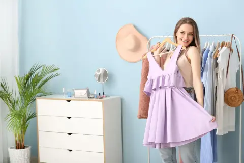 Ragazza sorridente prova un abito color glicine, pensando ai possibili abbinamenti vestiti per un look primaverile.