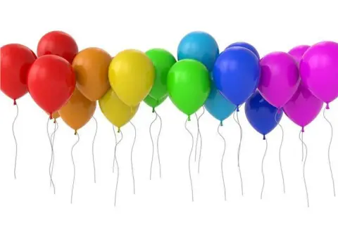 Kolorowe balony urodzinowe dla chłopca: czerwone, pomarańczowe, żółte, zielone, niebieskie i fioletowe, unoszą się na białym tle.