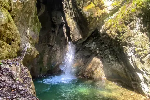 Piccola cascata in una gola rocciosa, con acqua cristallina che forma una pozza. Un luogo incantevole vicino al Lago di Garda.