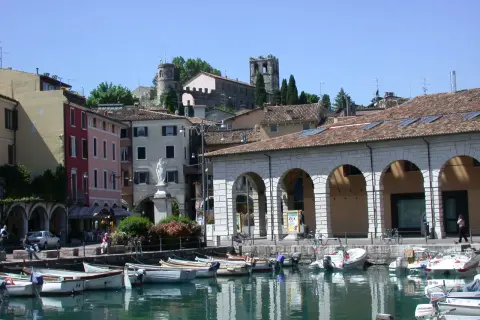 Porto di Desenzano: cosa vedere? Barche ormeggiate, case colorate e torri antiche sul lago.