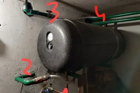 Bojler z termometrem i instalacją hydrauliczną. Widoczny odpowietrznik bojlera, zawory i rury.
