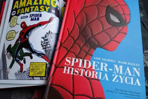 Okładka książki "Spider-Man: Historia Życia" z wizerunkiem Spider-Mana. Obok komiks "Amazing Fantasy" z pierwszym pojawieniem się bohatera.