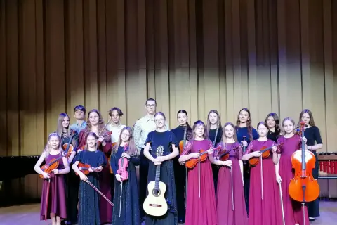 Młodzi muzycy, w tym Aleksandra Cieślik, gotowi do występu z instrumentami smyczkowymi i gitarą.