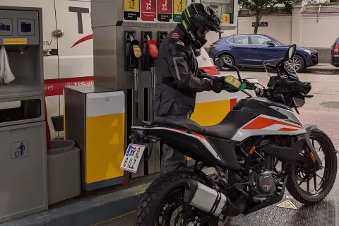 Motociclista repostando su moto 390 Adventure. La pregunta sobre qué gasolina usan las motos de 49cc es relevante para este tipo de vehículos.