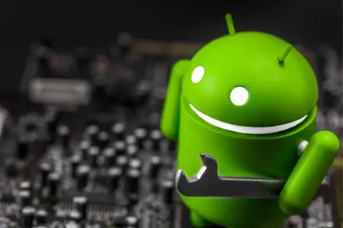 Zielony robot Android z kluczem, jakby wykryto nakładkę ekranową. W tle widać rozmazaną płytę główną.