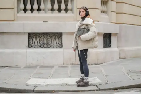 Modna dziewczyna w słuchawkach prezentuje stylowe stylizacje ze skarpetkami, które dodają charakteru jej zimowemu outfitowi.