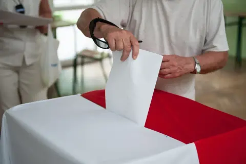 Mężczyzna wrzuca kartę do głosowania do urny. To ważny moment, nawet jeśli są to wybory poza miejscem zamieszkania.