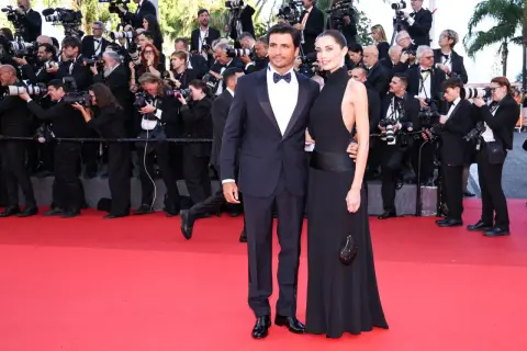 Rebecca Donaldson e il suo compagno sfilano sul red carpet, circondati da fotografi e fan.