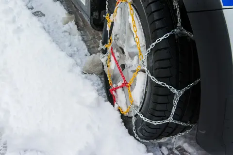 Łańcuchy na kołach 4x4 poprawiają przyczepność na śniegu. Widać je na oponie w zaspie.