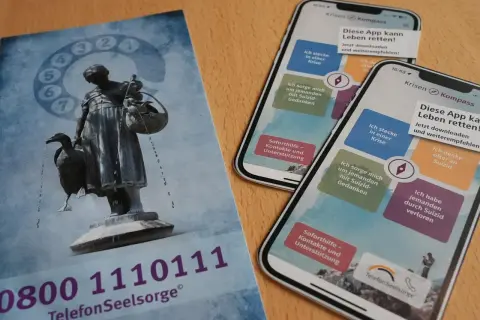 Flyer und Smartphones mit der App "Krisen Kompass" zeigen Wege zur rettung aus der not. Die Telefonseelsorge bietet Hilfe.