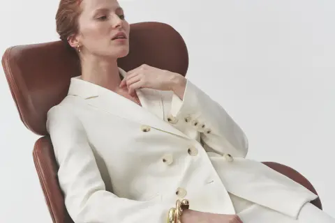 Elegancka kobieta w białym garniturze, zastanawia się, jaka bluzka do garnituru damskiego będzie idealna.