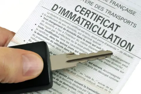 Clé de voiture sur un certificat d'immatriculation, symbolisant les documents d'achat d'une voiture d'occasion.