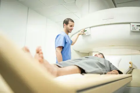 Un technicien ajuste les commandes d'un appareil d'IRM, prêt à examiner la prostate d'un patient allongé sur la table d'examen.