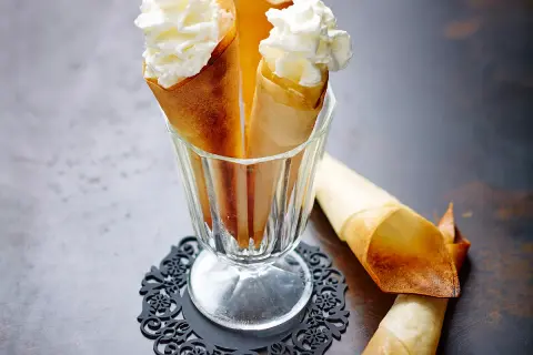 Délicieux cornets croustillants garnis de crème chantilly aérienne, prêts à être dégustés.