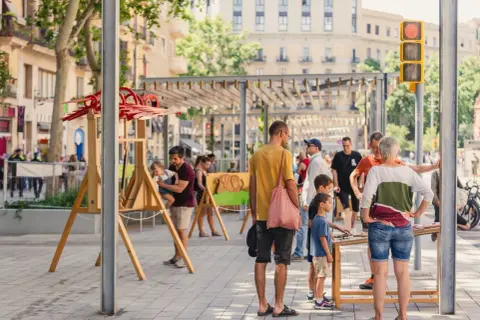 Gente disfrutando de unas vacaciones con niños en Cataluña, con juegos y actividades al aire libre en una calle peatonal.