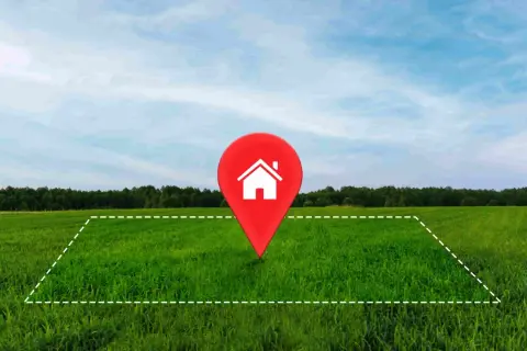 Un terreno verde con un marcador rojo de casa en el centro. Ideal para tu hipoteca para comprar terreno y construir tu hogar soñado.
