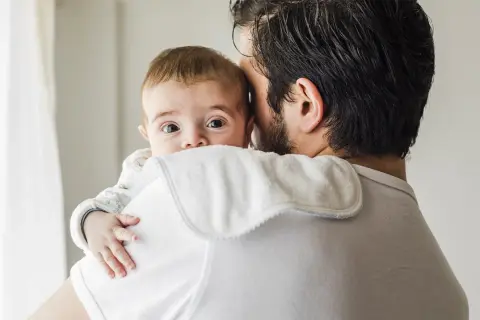 Tata tuli noworodka, który wygląda zza jego ramienia. Czy odbijać noworodka po karmieniu piersią?