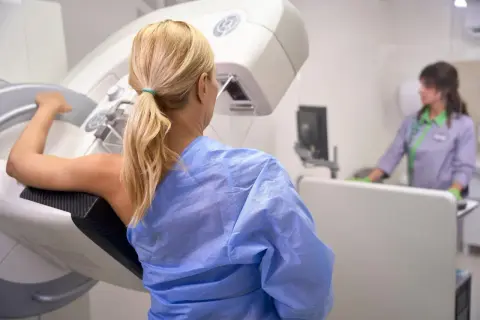 Kobieta w niebieskiej koszuli przygotowuje się do badania mammograficznego. Czeka na wyniki mojej mammografii.