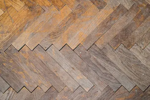 Parquet in legno con motivo a spina di pesce, usurato ma pronto per essere lucidato con rimedi della nonna per farlo brillare.