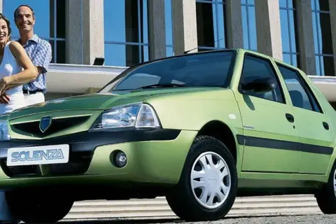 Szczęśliwa para obok zielonej Dacii Solenza. Wyobraź sobie podróż w 2026 roku tym niezawodnym autem.