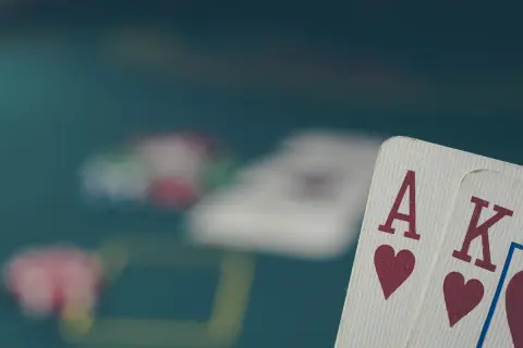 As i karty, as i król, pokazują starszeństwo kart. W tle rozmyte żetony i stół do gry.
