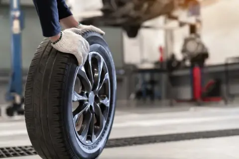 Mechanik w rękawiczkach trzyma oponę. Czy opony rowerowe do miasta z gładkim bieżnikiem zużywają się szybciej na kostce i asfalcie?