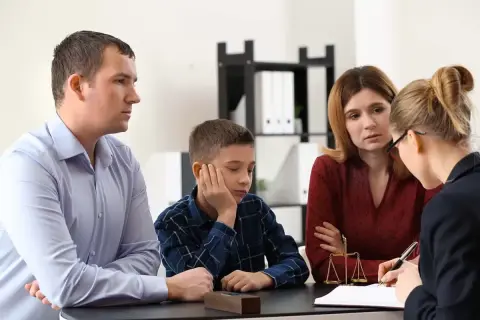 Rodzina z dzieckiem rozmawia z prawniczką przy biurku z wagą sprawiedliwości.
