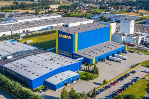Widok z lotu ptaka na fabrykę Lakma z niebiesko-żółtymi budynkami i parkingiem.