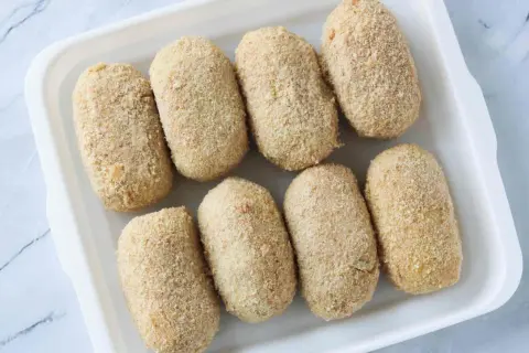 Ocho croquetas empanadas listas para cocinar en la airfryer.