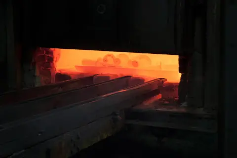 Żar rozgrzanego pieca, gdzie odbywa się hartowanie na wskroś. Metalowe elementy wchodzą w płomienie.