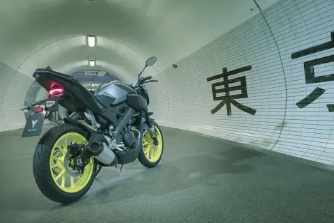 Yamaha MT-125 gris con llantas amarillas en un túnel con caracteres japoneses. ¡Lista para alcanzar su yamaha mt 125 velocidad maxima!