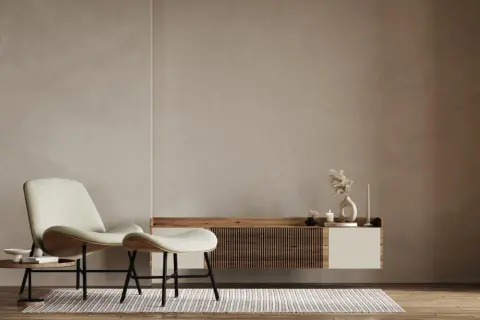 A minimalist living room with a textured limewash wall, a modern chair and ottoman, and a floating media console.