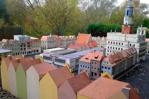 Miniaturowa zabudowa miejska z wieżą zegarową i kolorowymi domkami w skansenie.
