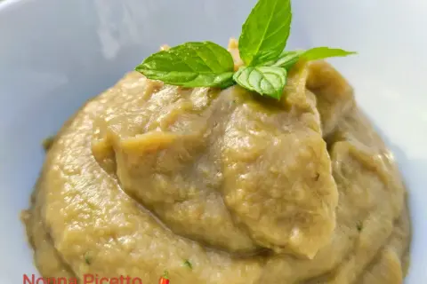 Patè di melanzane cremoso, perfetto per crostini, guarnito con foglie di menta fresca.