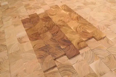 Patrón de suelo de madera cerezo con vetas circulares, algunas piezas más oscuras que otras, creando un efecto de degradado.
