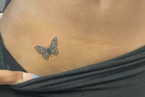 Delikatny tatuaż motyla na skórze, w miejscu intymnym, symbolizujący wolność i piękno.