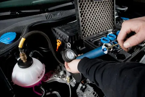 Controllo del radiatore macchina con kit di prova. Un tecnico usa uno strumento per verificare la pressione del sistema di raffreddamento.
