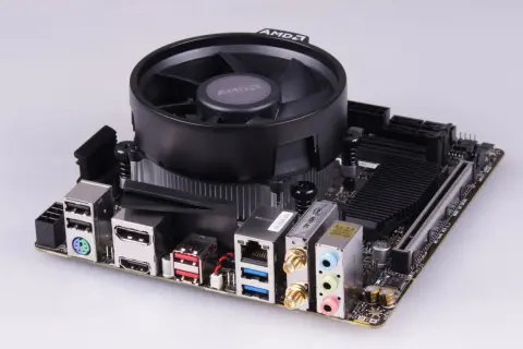 Mainboard mit AMD-Kühler, bereit für einen Ryzen 5 2400G Prozessor. Anschlüsse für USB, HDMI, LAN und Audio sind sichtbar.