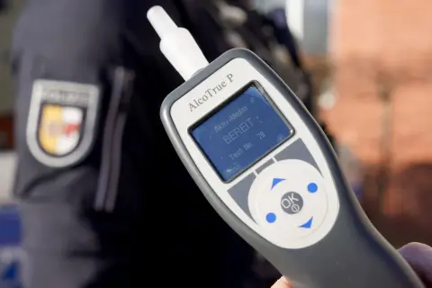 Polizist hält Alkoholtester. Das Gerät zeigt "BEREIT" an. Eine promille alkohol tabelle hilft, die Werte zu verstehen.