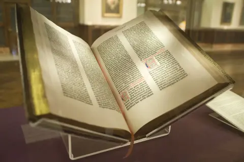 Un antiguo libro abierto, que podría ser la biblia, con páginas llenas de texto y decoraciones.