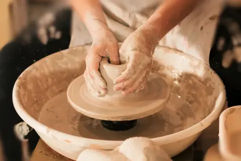 Mani esperte modellano l'argilla su un tornio, creando un pezzo unico di artigianato locale.