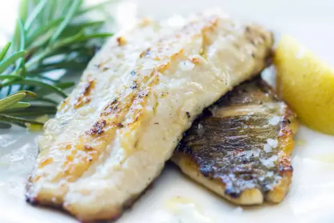 Zander grillen: Zwei saftige Filets mit knuspriger Haut, garniert mit Rosmarin und einer Zitronenspalte. Perfekt gegrillt!